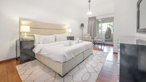 Habitación de hotel moderna con una cama grande, lámparas de noche, un escritorio y vistas a la ciudad por la ventana.
