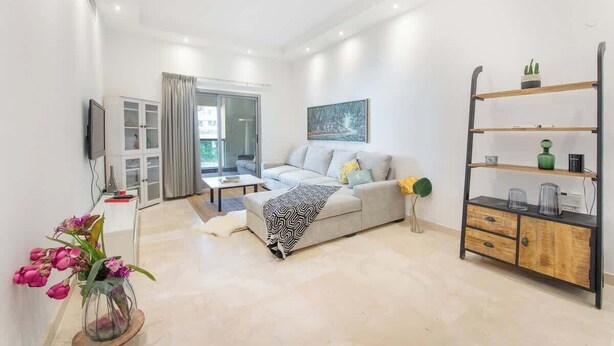 Una sala de estar moderna con sofá, mesa de centro y televisor sobre un mueble.