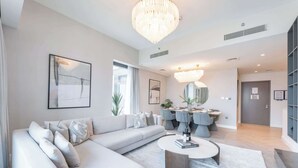 A modern living room with a sectional sofa, a round coffee table, and a dining area with a chandelier.