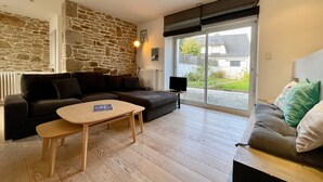 A cozy living room with a stone wall, a sofa, a coffee table, and a TV. - L'écrin de Manemeur-6p-Wifi-Jardin- near Quiberon center (Quiberon)