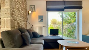 A modern living room with a stone wall, a sofa, a table, and a TV. - L'écrin de Manemeur-6p-Wifi-Jardin- near Quiberon center (Quiberon)