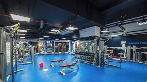A gym with various exercise equipment, benches, and dumbbells. - StayShort - Modern 2BR Retreat with Breathtaking Views in JBR (Dubai)