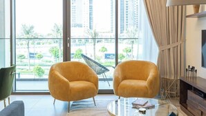 A modern living room with two yellow armchairs, a glass coffee table, and a view of a cityscape through large windows.