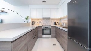 A modern kitchen with a built-in oven, a refrigerator, and a herringbone-patterned backsplash.