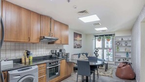 Une cuisine moderne avec des meubles en bois, un lave-linge encastré et un coin repas comprenant une table et des chaises.