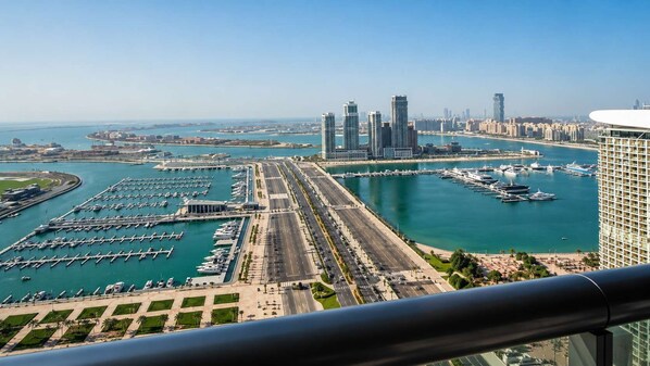 A marina with boats, a road leading to the marina, and high-rise buildings in the background. - Free housekeeping visits during your stay - StayShort - Scenic 2BR Apartment in Dubai Marina Near the Beach (Marina/JBR)