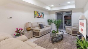 A modern living room with a sofa, armchairs, a coffee table, and a painting on the wall. - StayShort - Scenic 2BR Apartment in Dubai Marina Near the Beach (Marina/JBR)