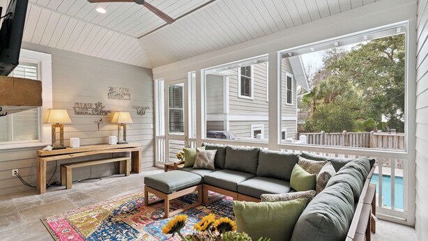 A cozy living room with a sectional sofa, a wooden bench, and a colorful rug. - Sunset Peak sleeps 12 with a pool (St Simons Island)