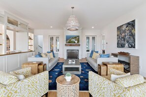 A spacious living room with a fireplace, sofas, a coffee table, and a large painting on the wall. - Sunset Peak sleeps 12 with a pool (St Simons Island)