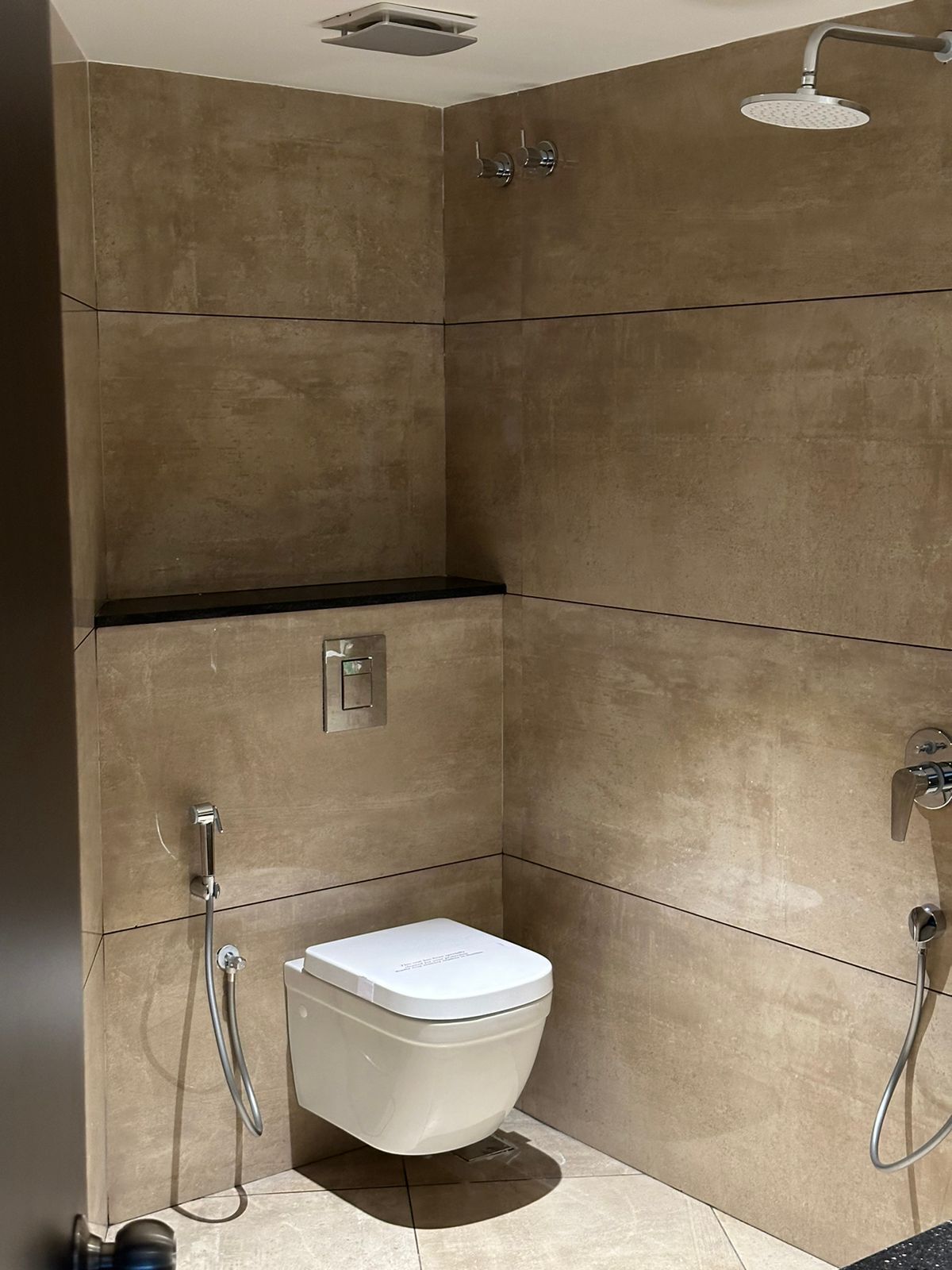 A modern bathroom with a shower, toilet, and a control panel.