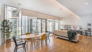 A modern, well-lit room with a large dining table, chairs, a sofa, and a 'Book Me' sign. - StayShort - Delightful 1BR in Bluewaters Island - JBR Walk! (Bluewaters Island)
