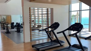 A spacious gym with treadmills, exercise bikes, and a large window offering a view of the ocean. - StayShort - Delightful 1BR in Bluewaters Island - JBR Walk! (Bluewaters Island)