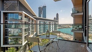 A modern apartment with a balcony overlooking a coastal view, featuring a dining area with chairs and a table. - StayShort - Delightful 1BR in Bluewaters Island - JBR Walk! (Bluewaters Island)
