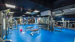 Un gimnasio con varios equipos de ejercicio, como mancuernas, bancos y máquinas de pesas.