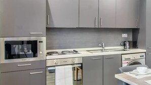 Una cocina moderna con armarios grises, horno empotrado, microondas y pileta.