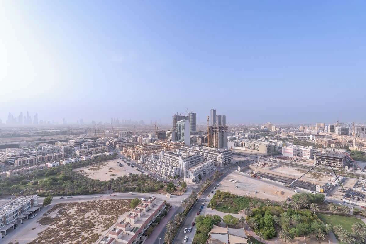 Vista aérea de un paisaje urbano con edificios modernos, calles y terrenos sin urbanizar.