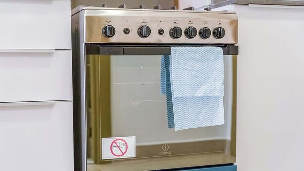 A stainless steel oven with a blue front panel and a control panel with multiple knobs.