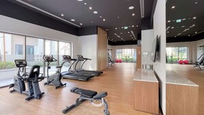 A modern gym with treadmills, elliptical machines, and a weight bench. - StayShort - Elegant & Spacious 4BR for Families in Creek Harbour (Dubai)