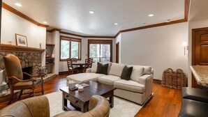 A spacious living room with a sectional sofa, a wooden coffee table, and a stone fireplace. - Strawberry Park 109 2 Bedroom Condo (Avon)