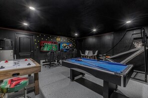 Une pièce équipée d’une table de billard, d’un baby-foot et d’un petit panier de basket.