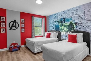 A hotel room with two beds, a Spider-Man couch, a mural, and a large window with curtains.