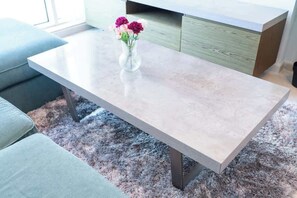 Eine moderne Küche mit Marmorarbeitsplatte, einer Blumenvase und einem grauen Shaggy-Teppich.