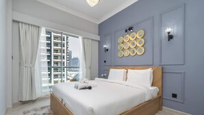 Moderni hotellihuone, jossa on suuri sänky, näköala kaupunkiin ja koristeellinen seinätaide.