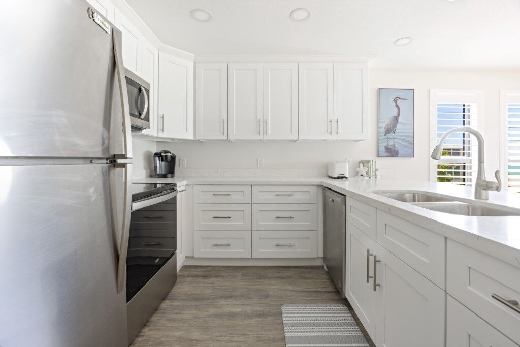 Una cocina moderna con armarios blancos, electrodomésticos de acero inoxidable y una isla grande con fregadero.