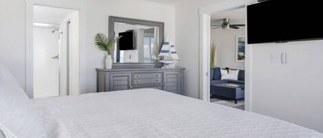 A bedroom with a large bed, a dresser, a mirror, and a TV.