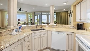 Una cocina moderna con encimeras de granito, lavavajillas y vistas al exterior.