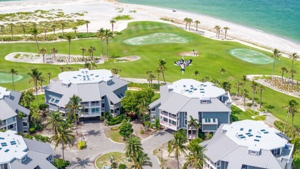 Vista aérea de un complejo turístico con varias edificaciones, un campo de golf y una playa.