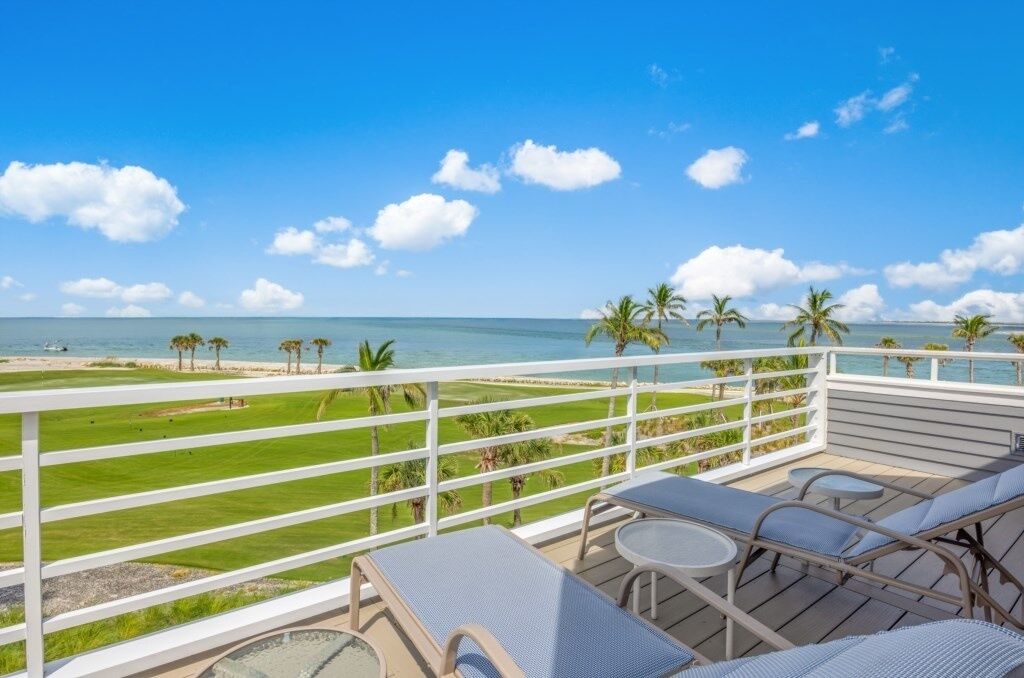 Ein Balkon mit Blick auf Strand und Meer, ausgestattet mit Liegestühlen und einem kleinen Tisch.