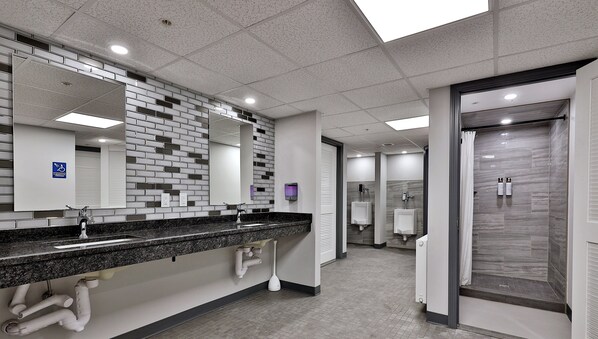 A modern restroom with a black granite countertop, a tiled wall with a brick pattern, and a mirror above the sink.