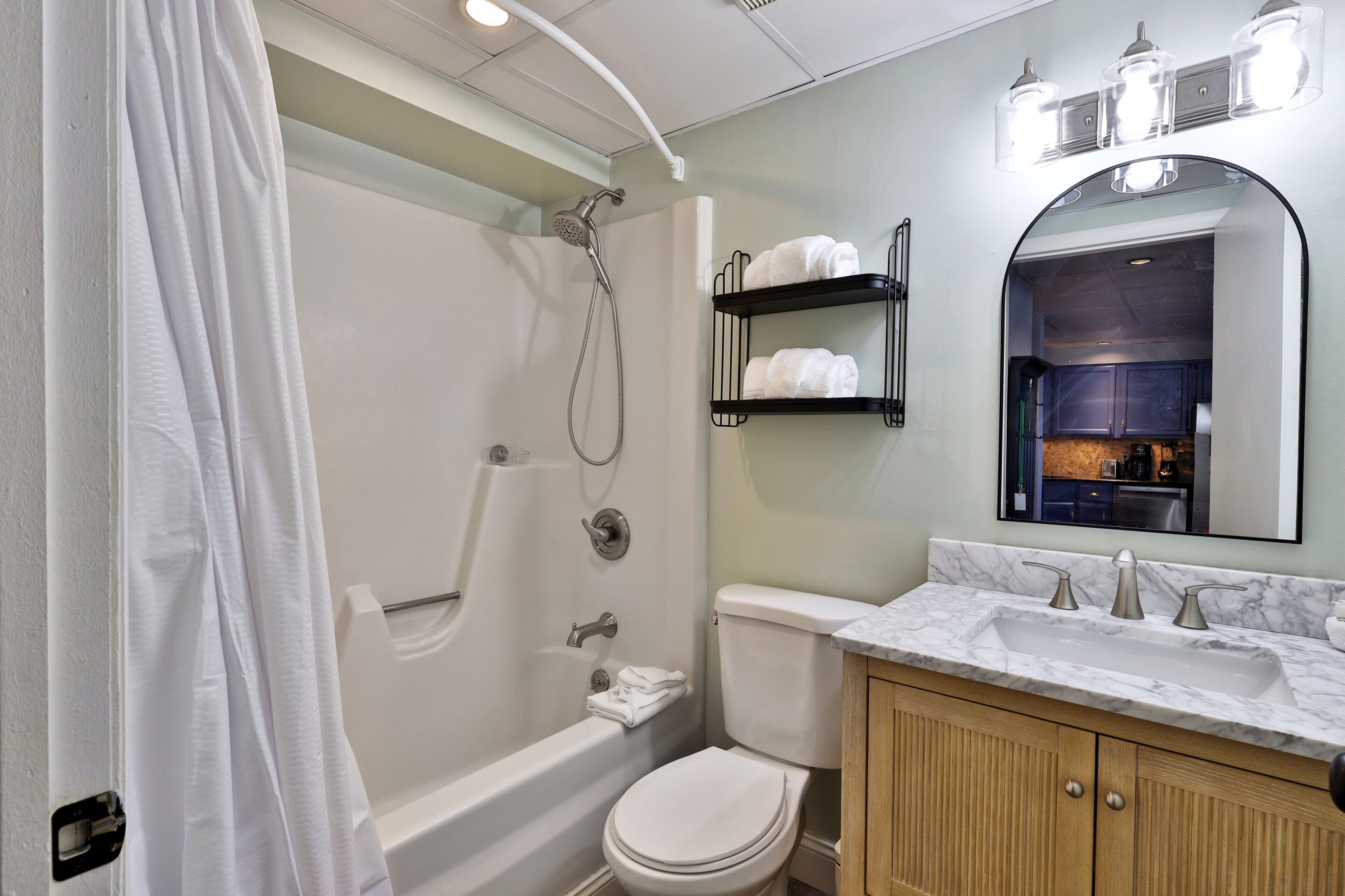 A modern bathroom with a bathtub, toilet, and vanity with a mirror.