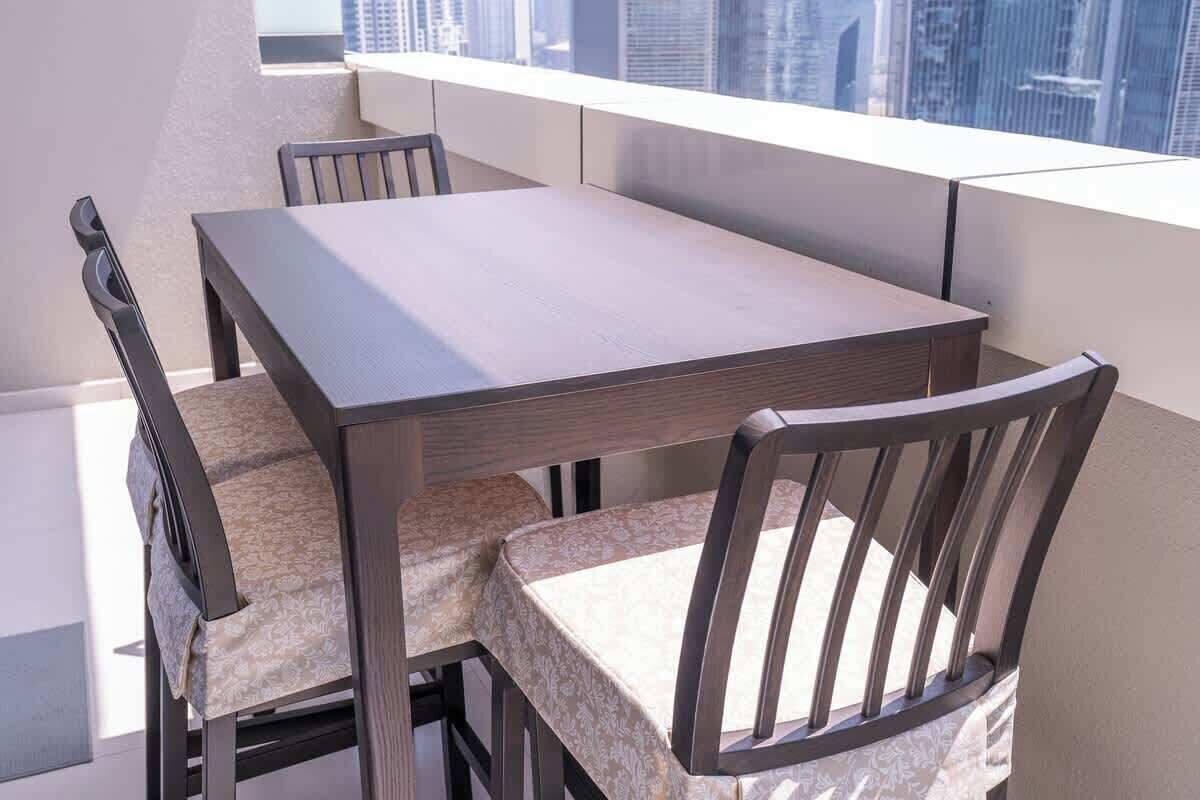 A modern dining area with a rectangular table and four chairs, featuring a city view through large windows.