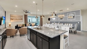 Una cocina moderna con encimeras de granito, iluminación colgante y una isla central.