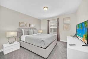 A bedroom with a bed, bedside tables, a TV, and a window with curtains. - Mickey's Hidden Gem Luxury Pool Home! 4 Bedroom Townhouse (Davenport)
