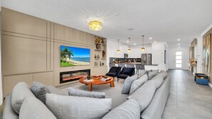 A modern living room with a large gray sofa, a fireplace, and a television. - 2900penolpe 9 Bedroom Home (Kissimmee)