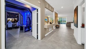 A modern interior with a reception desk, a seating area, and a view to the outside. - 2900penolpe 9 Bedroom Home (Kissimmee)