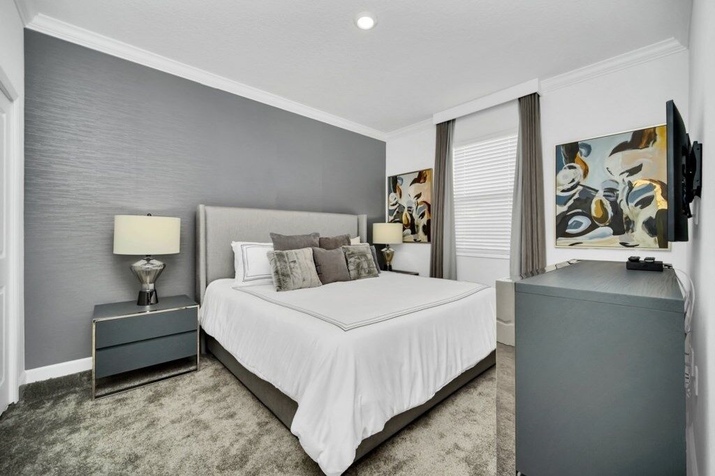 A modern bedroom with a large bed, bedside tables, a dresser, and abstract artwork on the walls.