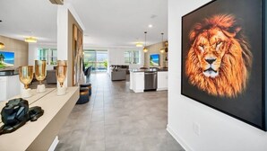 A modern kitchen with a large island, a dining area with a view, and a large framed picture of a lion. - 2900penolpe 9 Bedroom Home (Kissimmee)