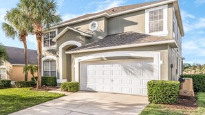 A two-story house with a garage, palm trees, and a well-maintained lawn. - Emerald Island Large 8 Bed Home Golf Resort 8 Bedroom Villa (Kissimmee)