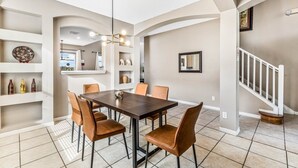 A dining area with a dark wooden table, six brown chairs, and a modern chandelier. - Emerald Island Large 8 Bed Home Golf Resort 8 Bedroom Villa (Kissimmee)