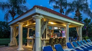 A covered outdoor seating area with lounge chairs and a bar. - Emerald Island Large 8 Bed Home Golf Resort 8 Bedroom Villa (Kissimmee)
