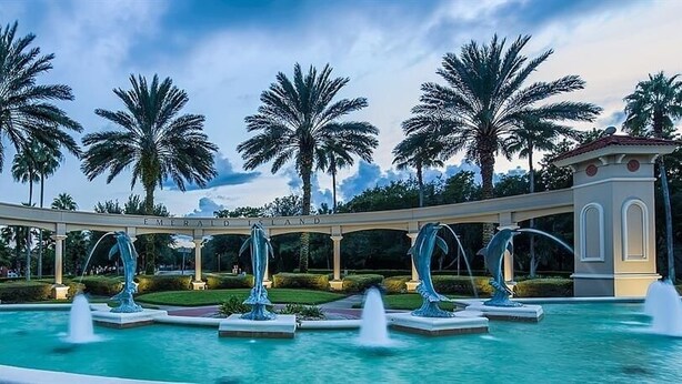 A pool area with multiple fountains, palm trees, and a gazebo with the text "Emerald Isle." - Emerald Island Large 8 Bed Home Golf Resort 8 Bedroom Villa (Kissimmee)