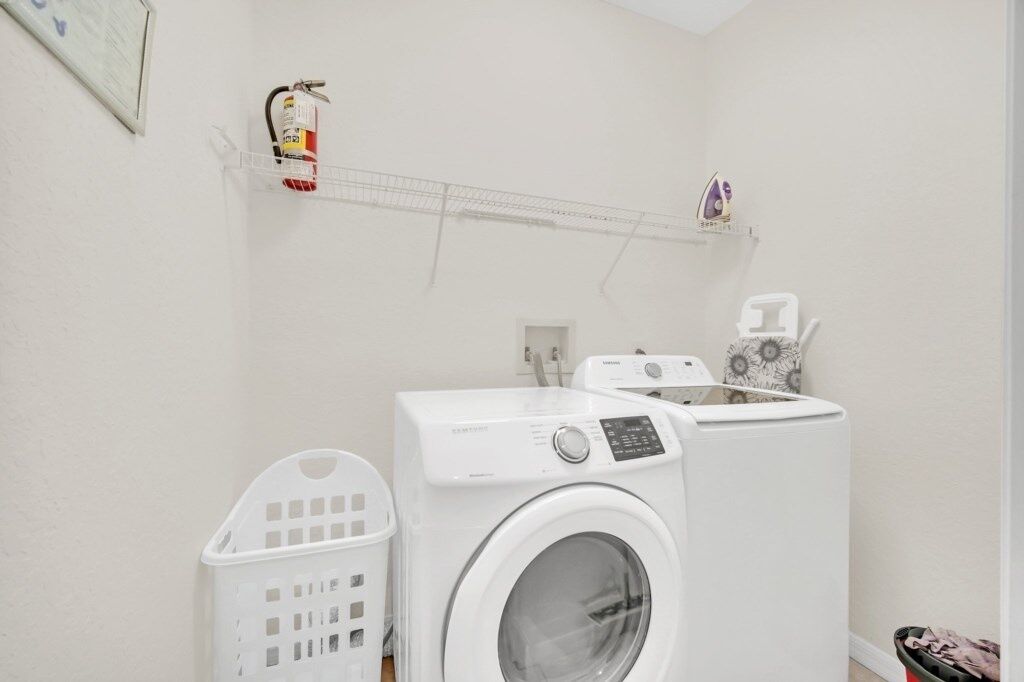 A laundry room with a washing machine, dryer, and a shelf with laundry supplies.