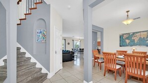 A spacious living area with a dining table and chairs, a staircase, and a world map on the wall.