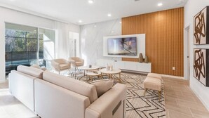 Ein modernes Wohnzimmer mit großem Fernseher, beigefarbenen Sofas und einer Wand als Holzdekor.