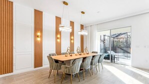 Ein moderner Essbereich mit Holztisch und grau gepolsterten Stühlen, Holzvertäfelung an den Wänden und einem großen Fenster mit Blick ins Freie.