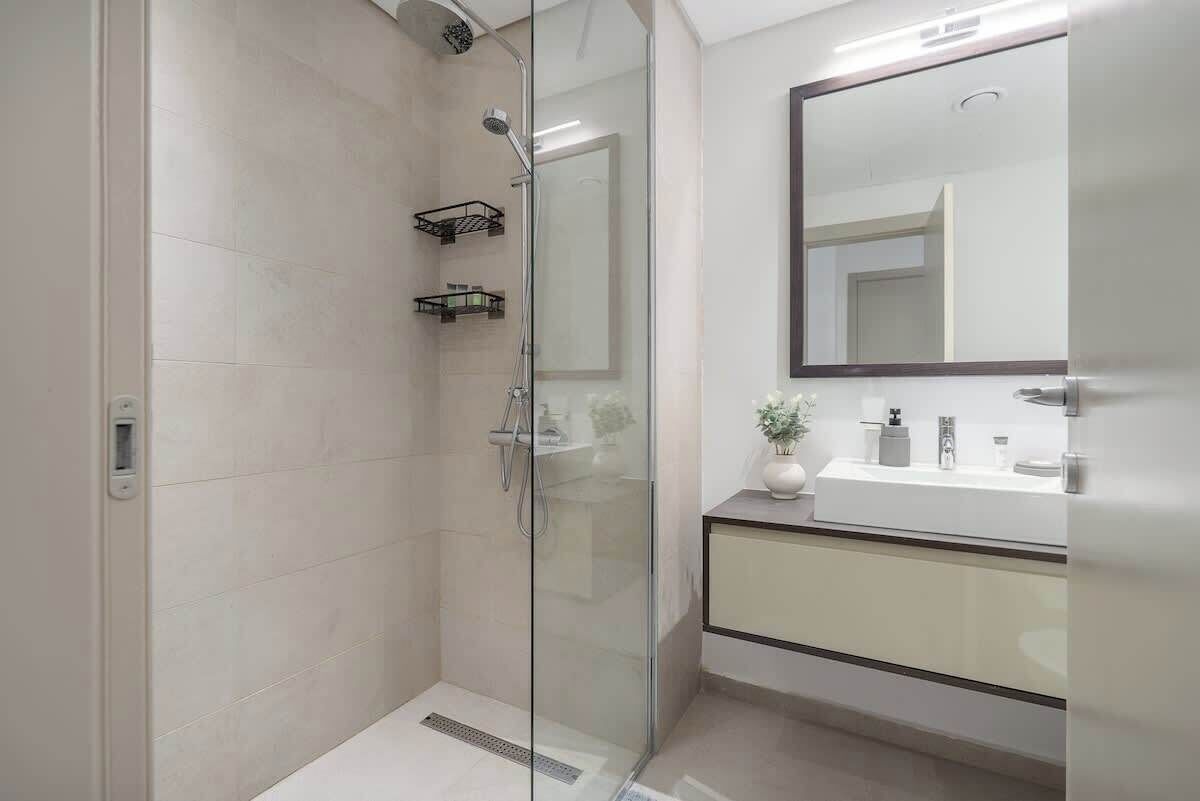 A modern bathroom with a glass shower enclosure, a sink with a mirror, and a cabinet.